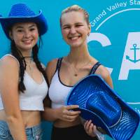 two students posing with blue hats in front of CAB backdrop at Laker Kickoff photo booth
